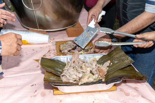 Unknown people serving homemade barbacoa on plates with maguey leaves