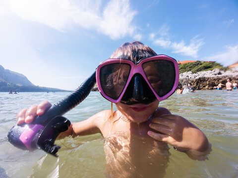Little kid snorkeling in the sea wearing pink diving mask