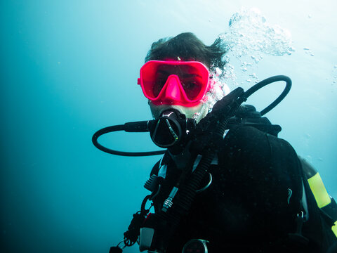 Diver is exploring the ocean with scuba gear and pink mask