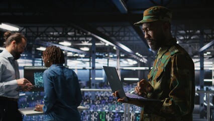 Army IT specialist in data center using laptop to defend networks against cyber threats. Military command center admin using notebook to identify potential intrusions or malicious activities,