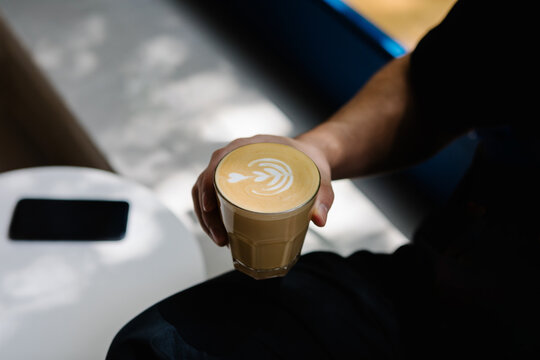 An unidentified individual gripping and drinking a latte