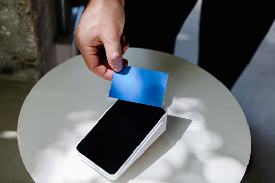 A hand offering a tap payment card to process a secure purchase