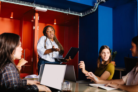 Black woman presenting at a board meeting with female leaders