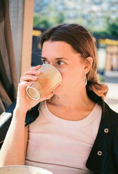 Woman drinking from ceramic cup at outdoor cafe