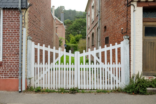 White Wooden Gate Between Brick Houses