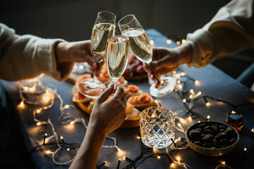 Friends celebrating Christmas or New Year eve party with champagne or sparkling wine.