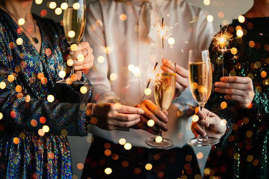 Friends celebrating Christmas or New Year eve party with Bengal lights and champagne. - Powered by Adobe