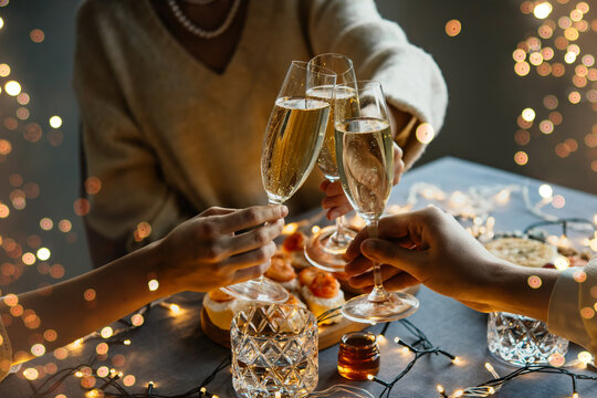 Friends celebrating Christmas or New Year eve party with champagne or sparkling wine.