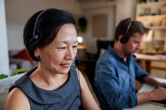 Two people wearing headsets working at their desks.
