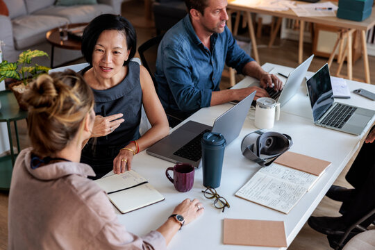 Team meeting with laptops, notebooks, and VR headset.