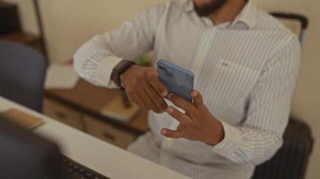 Man using smartphone in office wearing striped shirt checking smartwatch with focused expression indoors desktop background technology scene. - Powered by Adobe