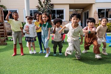 Diverse group of children playing and running on green grass.