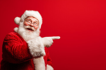 Naklejka premium Smiling Santa Claus pointing to empty space for text or logo. Designed for marketing materials and festive promotions.