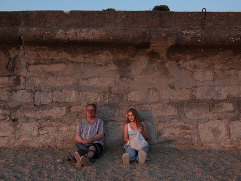 Father and daughter sit to watch sunset