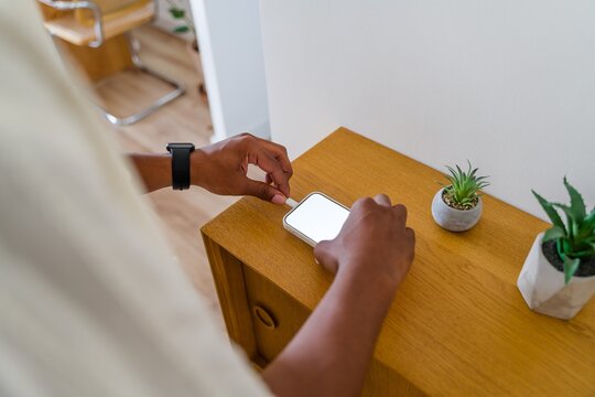 Man plugging charging cable into smartphone