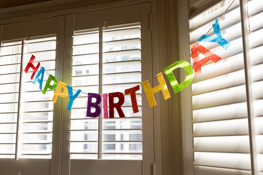 A Happy Birthday garland hanging in front of a window
