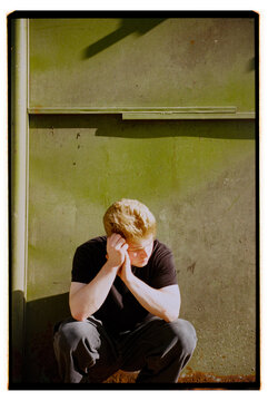 Young man thinking by green wall