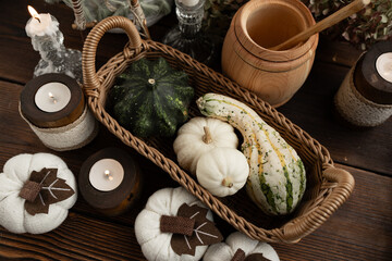 Autumn harvest. a wicker basket with a green pumpkin and white decorative pumpkins on a wooden table with candles on a background of hydrangeas.