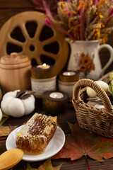 lose-up of a honeycomb on a white plate surrounded by a wooden barrel and a cup. a warm and rustic atmosphere. Bee honey.