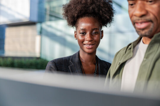 Business colleagues review documents outside modern office building.