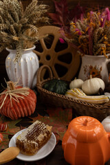 Rustic autumn decor. There are white and orange pumpkins in the basket, surrounded by dried flowers. The wooden wheel adds charm to the dish.