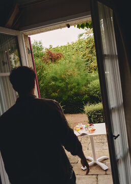 Man Stepping Outside to Enjoy Breakfast in a Garden Setting