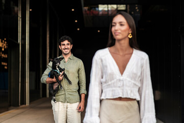 Loving man gazes partner with affection holding pet dog