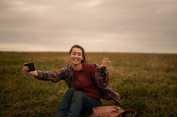 Young woman making video call in a field while hiking