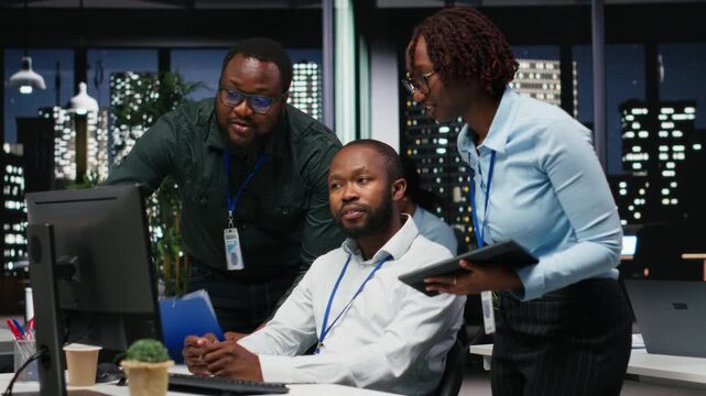 African american staff members consulting each other for monthly reports, reviewing KPI data insights for business productivity late at night. Collaboration between employees for success. Camera B.