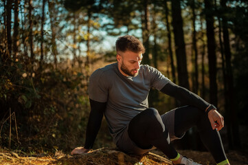 Male athlete resting after workout in forest during autumn