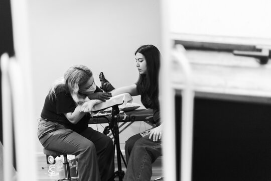 Tattoo artist working on client&rsquo;s forearm in studio