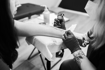 Tattoo artist inking floral crescent design in black and white