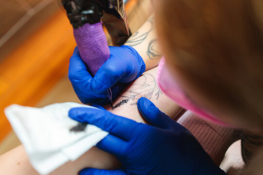 Tattoo artist inking floral crescent moon design