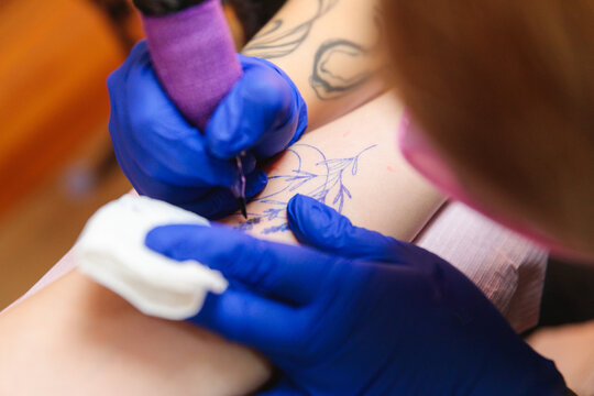 Tattoo artist inking floral design with precision