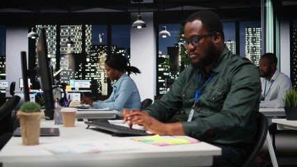 Black coworkers team monitoring forecast data for a new monthly analysis in dark office, utilizing reports and insights to plan reports and statements. Goal setting after hours. Camera A. - Powered by Adobe