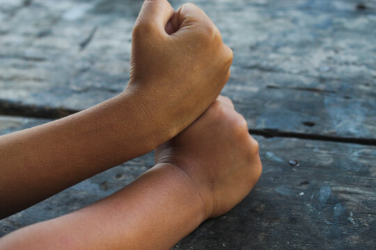 close up of two children's hands playing the traditional game of thumb fighting on an old wooden surface