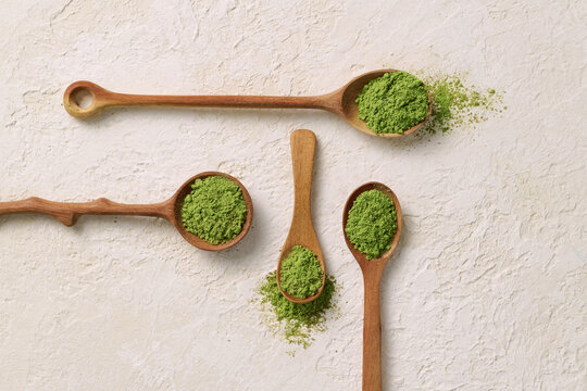 Wooden Spoons With Matcha Green Tea Powder On Textured Background