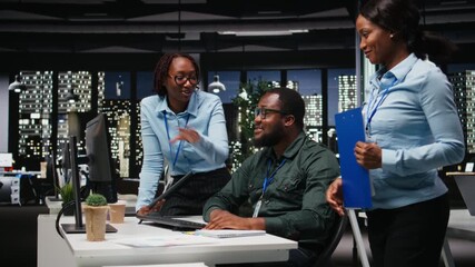 Team of black colleagues doing teamwork on a project with financial forecasting, projecting data to expand the enterprise activity and profit. Teamwork in workspace to ensure objectives. Camera A. - Powered by Adobe
