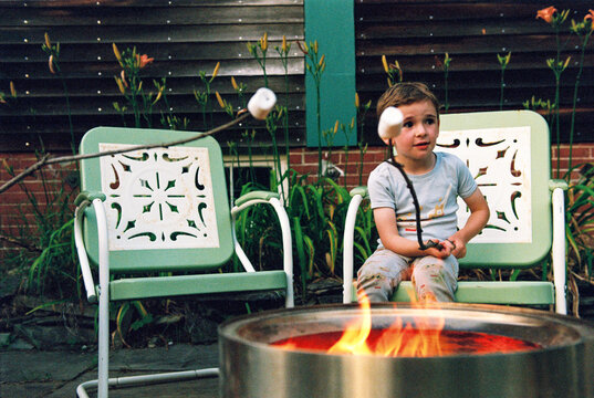 Child roasts marshmallow in backyard fire pit
