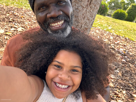 Grandfather and granddaughter taking a selfie in the park. UGC