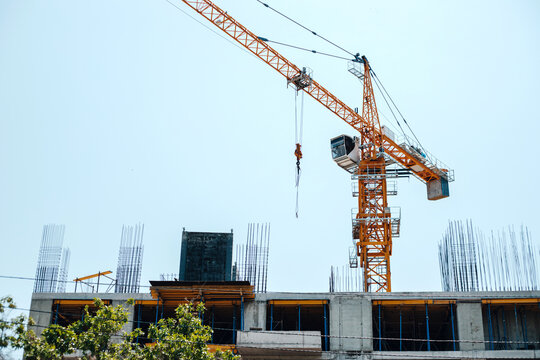 Construction crane near new building against blue clear sky.