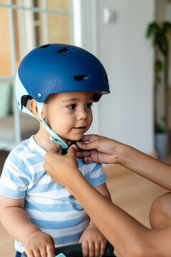 child fastening her brothers helmet 