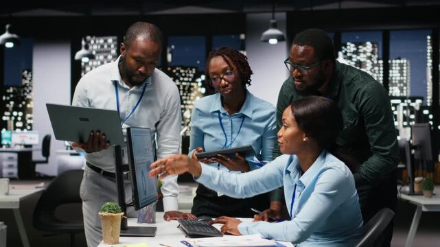 Black team of male consultants reviewing data analytics on desktop, building a vision and business strategy to accomplish objectives and success. Mindset for teamwork late at night. Camera B.