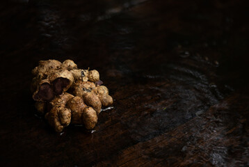 Black galingale or Kaempferia parviflora rhizomes on old wooden background.
