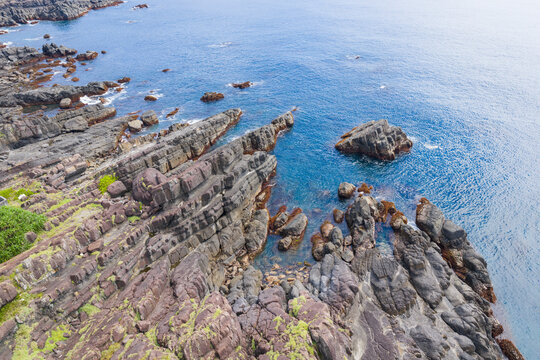 Aerial View of Rugged Rocky Coastline with Greenery and Blue Sea