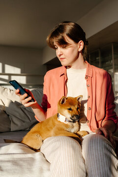 Woman checking aap of GPS tracker on smartphone while holding dog 