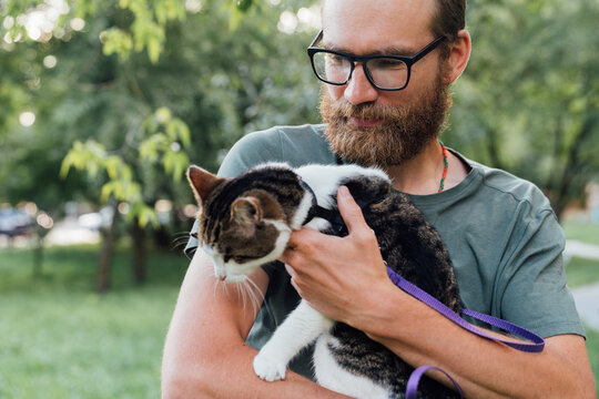 Man Holding Leashed Cat Outdoors
