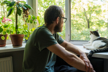 Man sitting by window with resting cat
