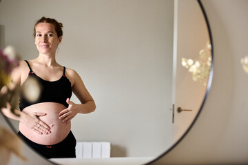 Proud pregnant woman looking at her belly