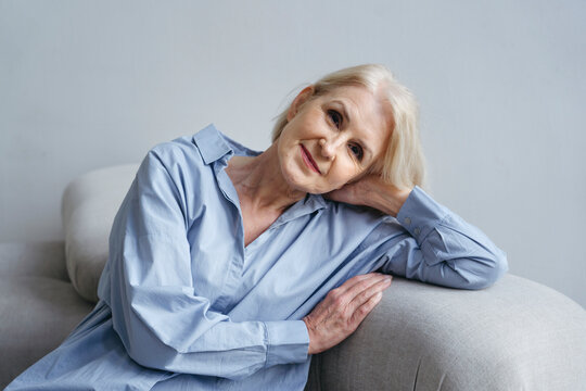 Older Woman Relaxing on a Couch With a Thoughtful Expression